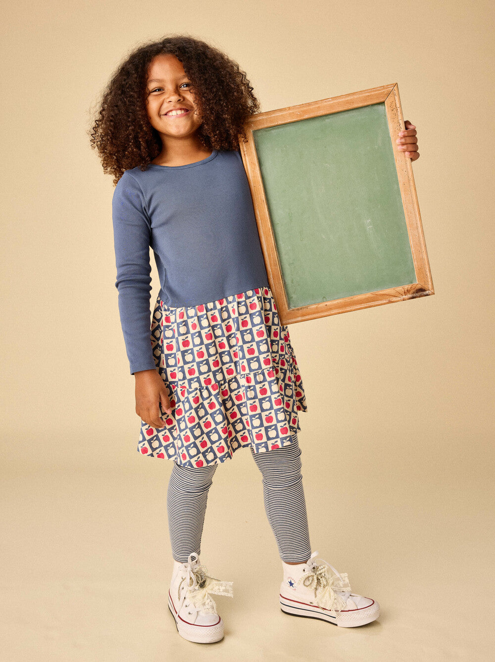 Child holding a small chalkboard with a neutral background
