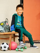 Child sitting on a chair with sports equipment and a skateboard
