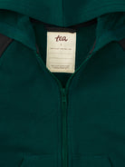 Close-up of a green hoodie with a visible brand tag.
