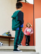 Two children on a staircase with one holding a pink ball.