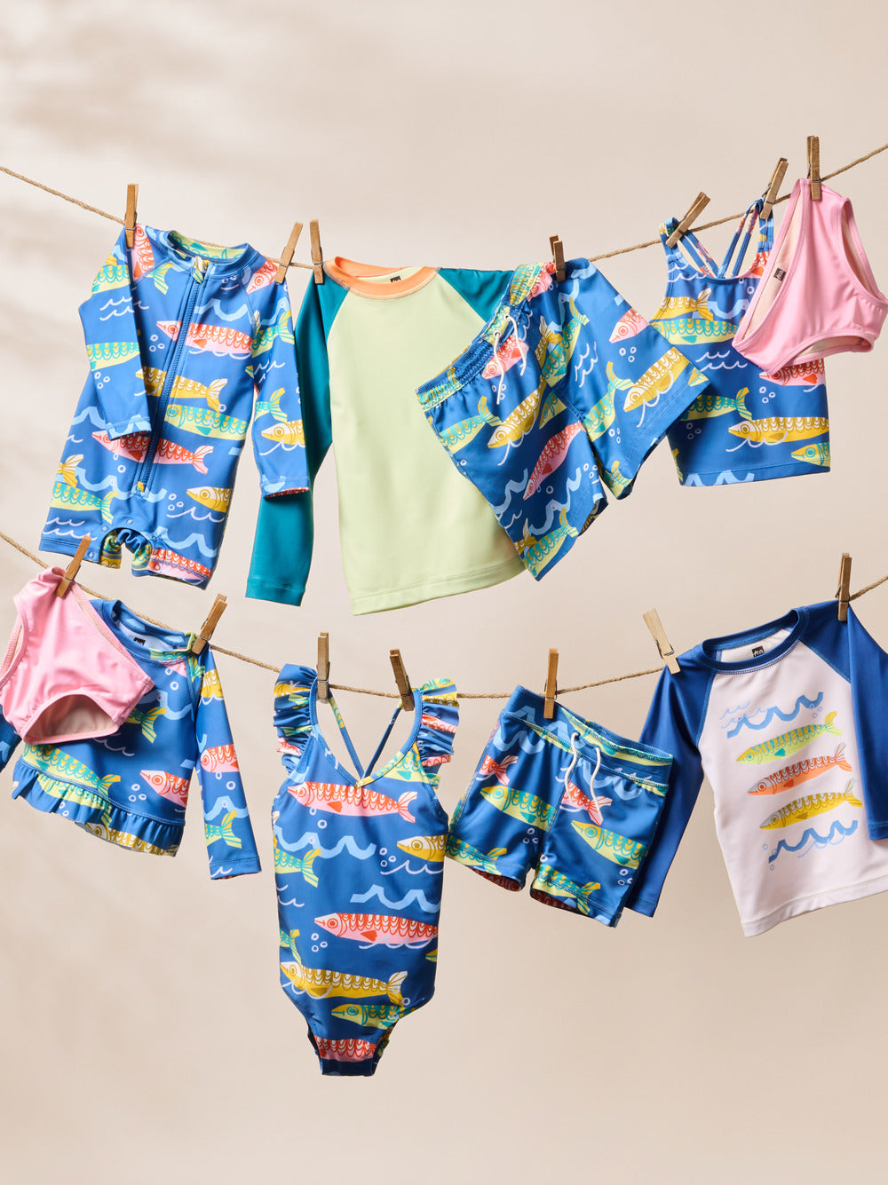 Children's swimwear with fish pattern hanging on a clothesline against a beige background