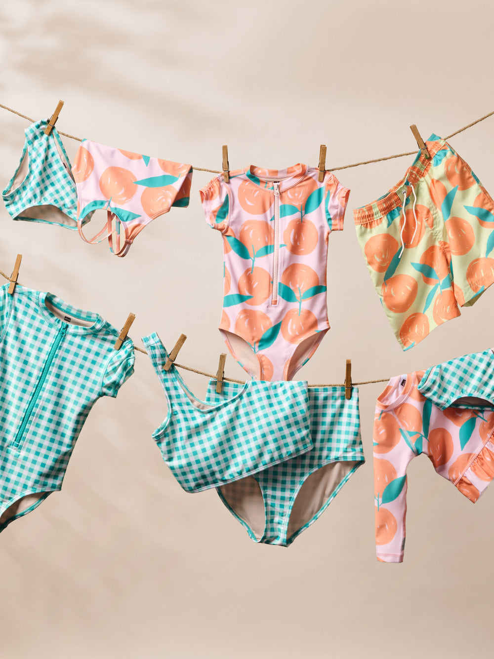 Colorful children's swimsuits hanging on a clothesline against a beige background
