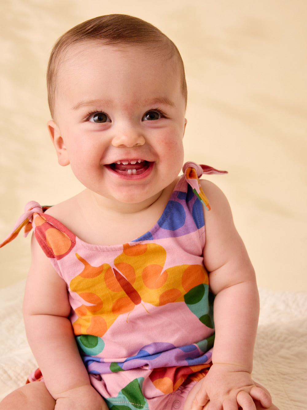 Baby wearing a colorful dress with a plain background