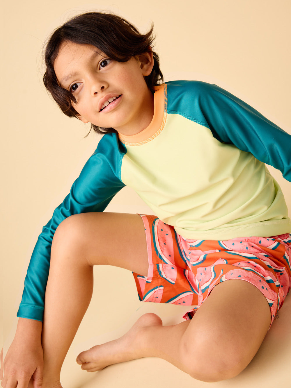 Child wearing a colorful shirt and shorts on a beige background