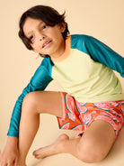 Child wearing a colorful shirt and shorts on a beige background