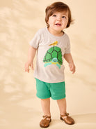 Child wearing a t-shirt with a turtle design on a beige background