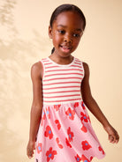 Young girl wearing a pink and white striped dress with floral pattern on a beige background
