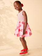 Young girl wearing a pink and white striped dress with floral pattern on a beige background