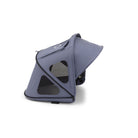 A stroller canopy in a muted slate blue-gray color, shown from a side angle with its hood up, featuring mesh windows and black trim, set against a plain white background.