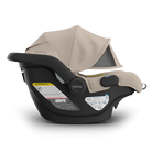 Baby car seat with beige canopy and black base on a white background