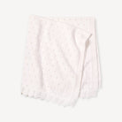 A folded white knit baby blanket with a delicate eyelet pattern and ribbed scalloped edges, shown on a light off-white background.