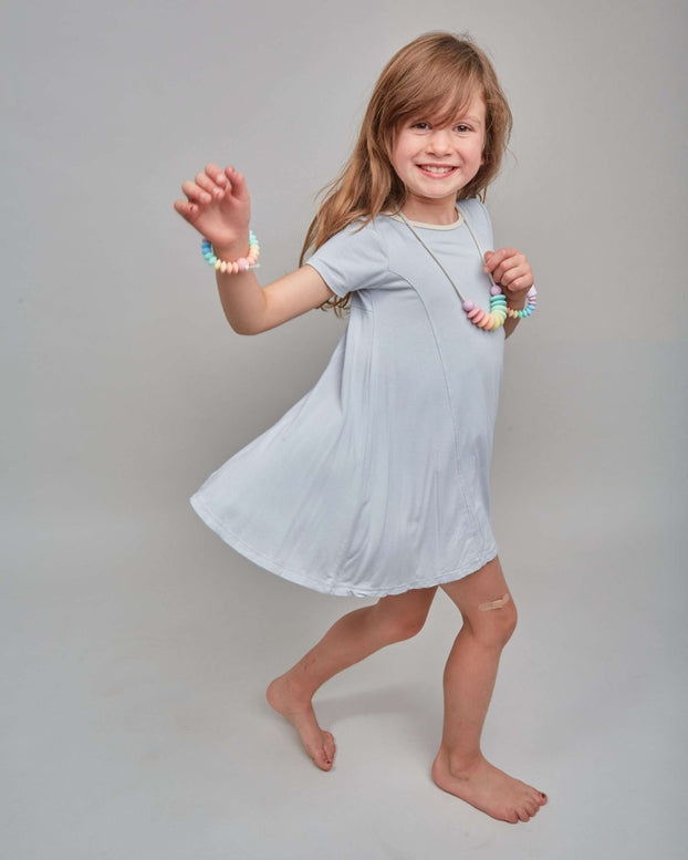 Young girl in a light blue dress posing against a plain background