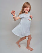 Young girl in a light blue dress posing against a plain background
