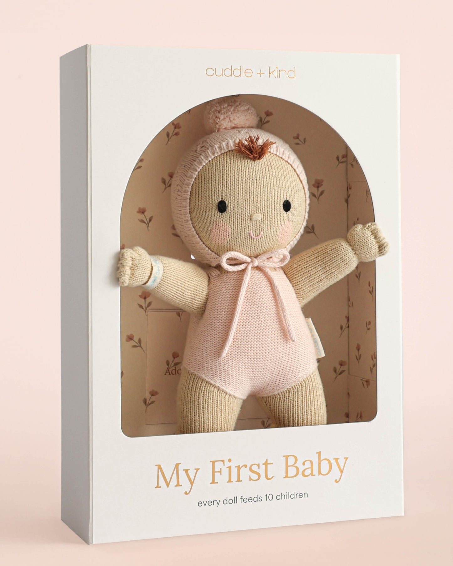 Cuddle + Kind doll in packaging with 'My First Baby' text on a pink background