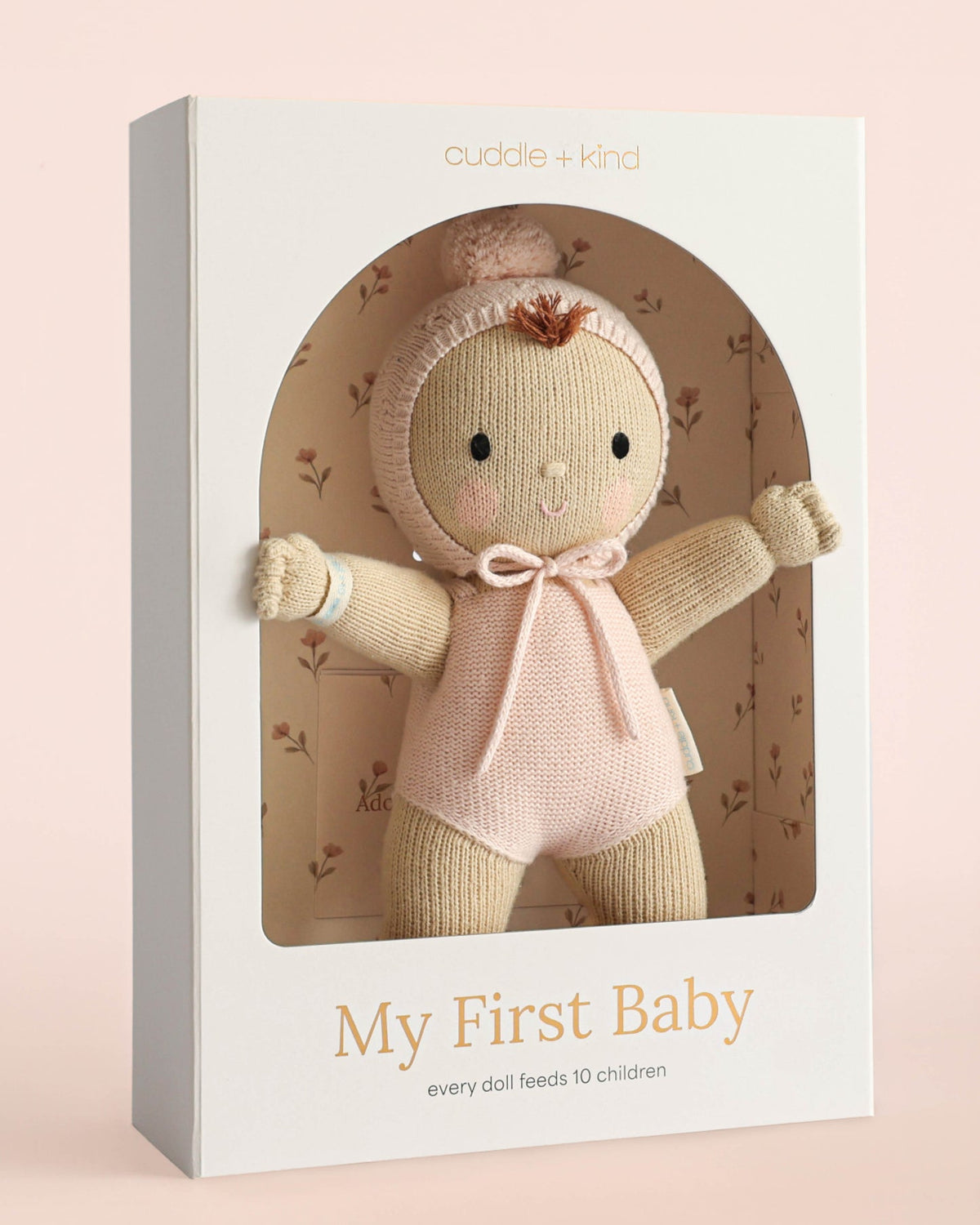 Cuddle + Kind doll in packaging with 'My First Baby' text on a pink background