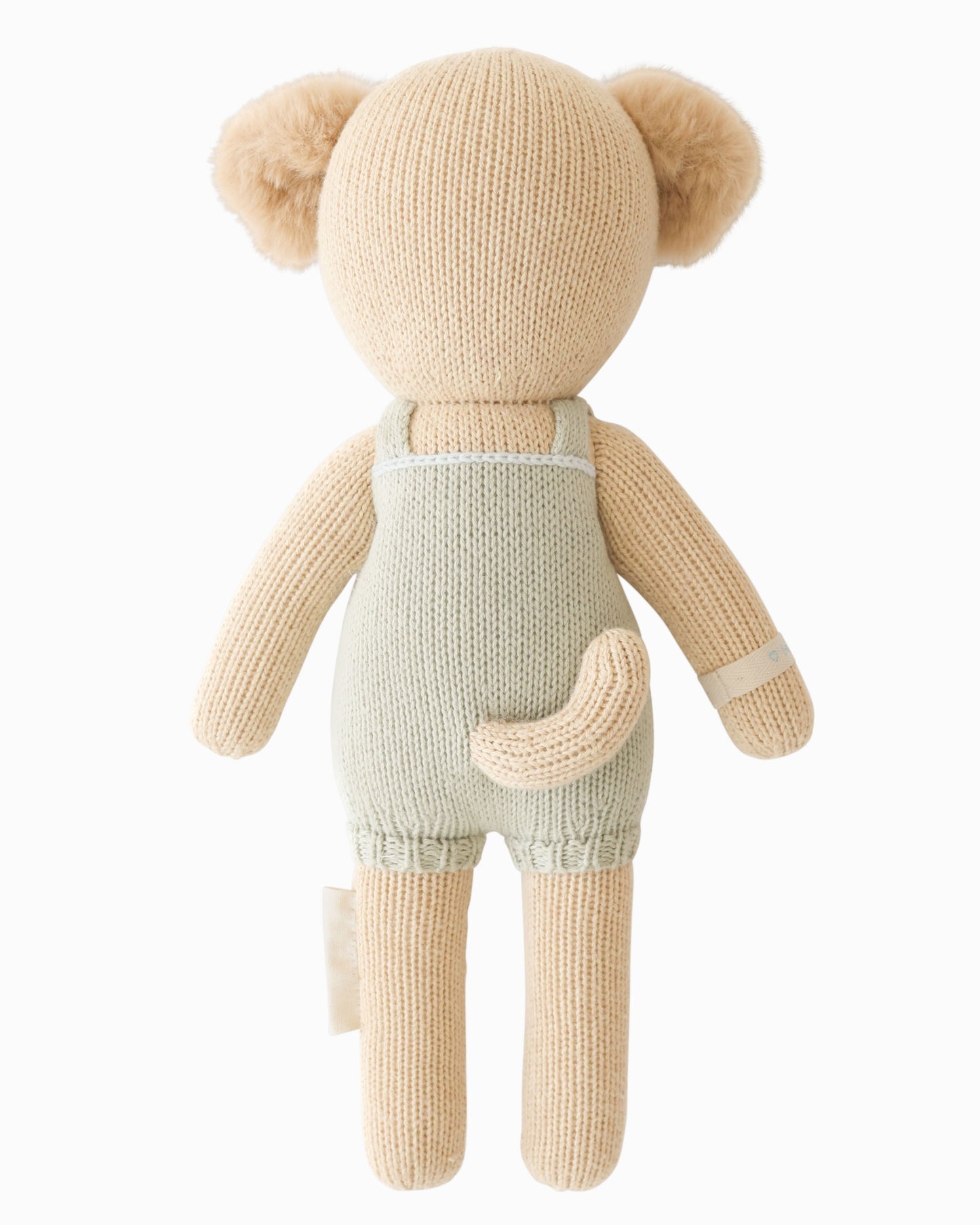 Knitted teddy bear wearing a light green romper on a white background
