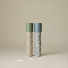 Two Mushie paper kaleidoscopes standing vertically against a light background, featuring the Floral Combo pattern with green caps and botanical floral illustrations.