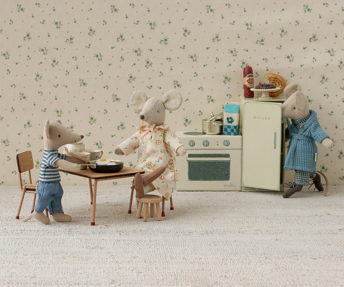 Miniature diorama of mice in a kitchen setting with floral wallpaper.