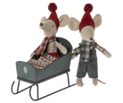 Two Maileg mouse plush toys with winter clothing—one seated inside a green wooden toy sleigh and the other standing beside it against a transparent background.