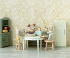 Miniature scene with toy mice around a table in a room with decorative wallpaper.