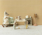 Maileg miniature nursery scene featuring a standing adult mouse in a floral nightgown next to a white metal baby crib, with a baby mouse sleeping on a changing table, a small elephant toy, a teapot on a fireplace mantle, and a floral floor lamp.