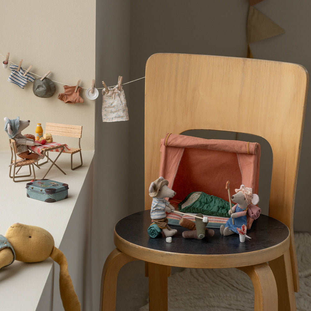 Wooden chair with a small toy setup in a cozy room with toys and furniture.