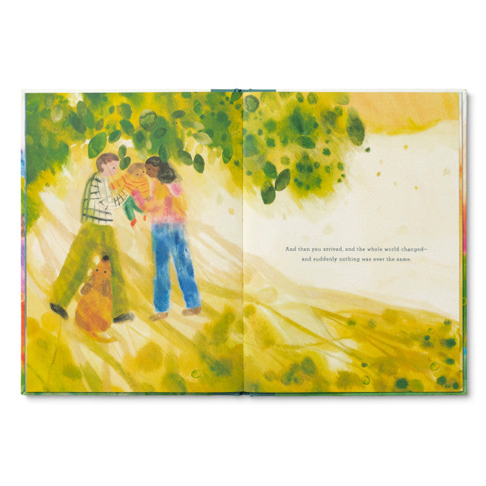 Illustrated book open to a page with a family and dog under a tree