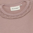 Close-up of a ribbed pink garment with lace trim and a visible brand label.