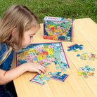 Child playing with a puzzle of the United States on a wooden table outdoors.