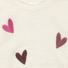 Close-up pattern of small hearts in dark brown, pink, and light gray.