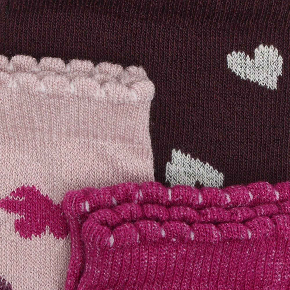 A set of patterned children's knit socks and leg warmers with decorative ruffles and heart designs.