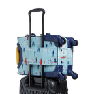 Rear three-quarters view of a light blue State Bags Mini Logan carry-on suitcase featuring an all-over airplane pattern, a black telescopic handle, 360-degree spinner wheels, and dark blue trim details against a transparent background.