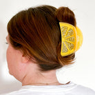 Person with a yellow lemon-shaped hair clip in their hair against a white background