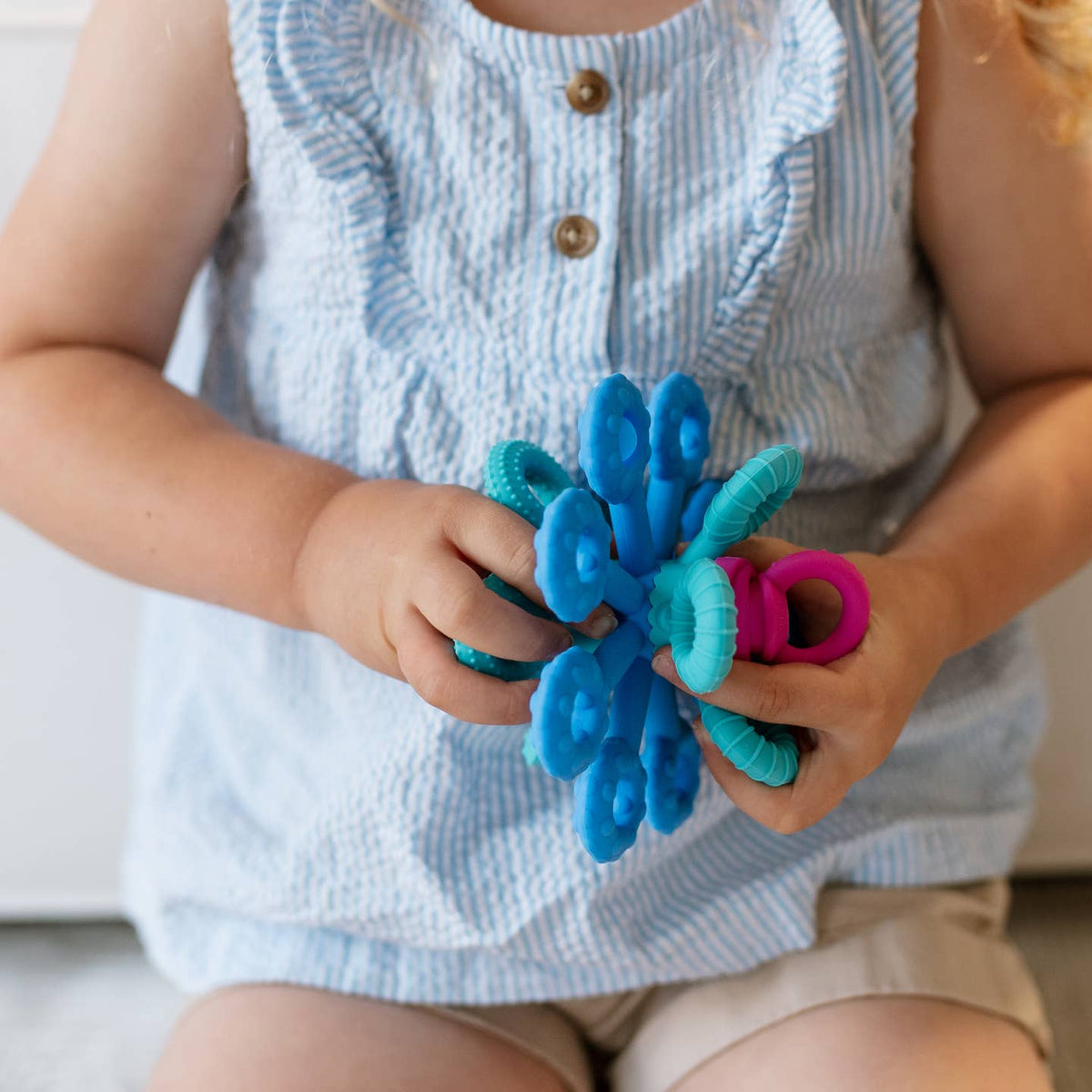 Child holding a blue and pink flower-shaped toy