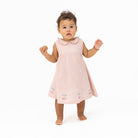 Baby wearing a pink dress with cherry design on a white background