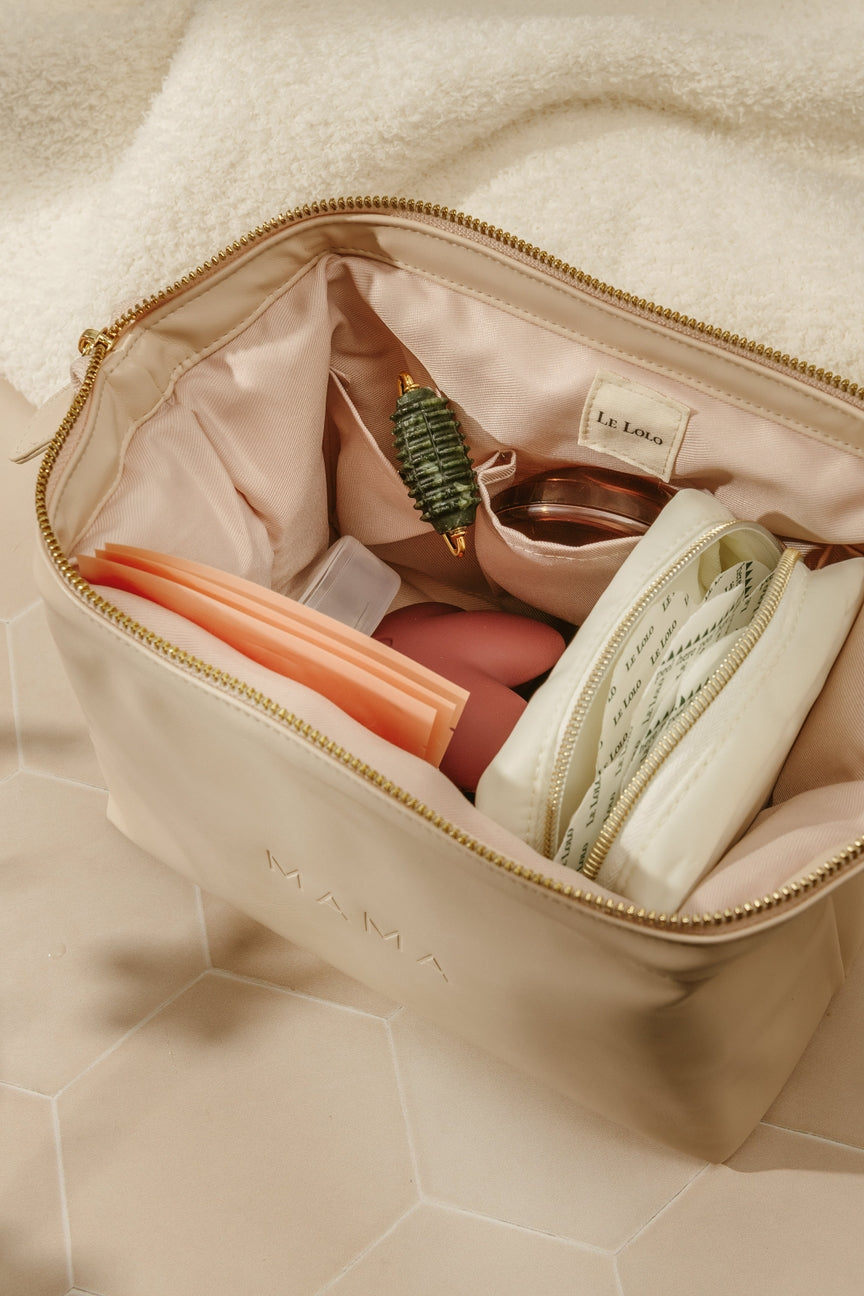 Beige makeup bag with cosmetic items on a beige surface