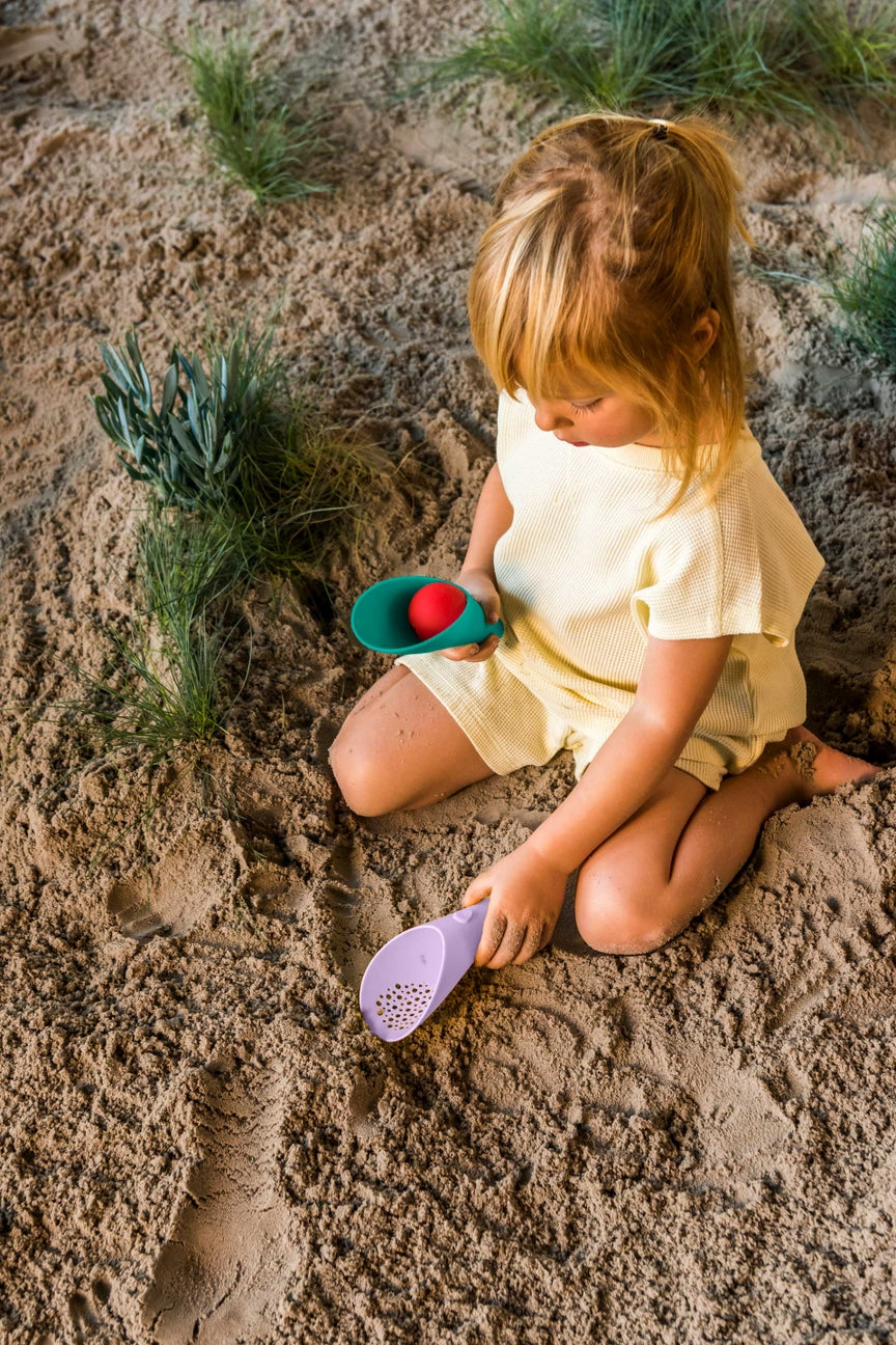 Child playing in sand with toys on a beach