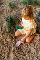 Child playing in sand with toys on a beach