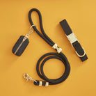 Black dog leash with gold hardware and a black pouch on a mustard yellow background