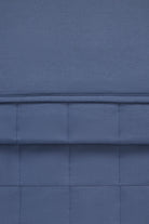 A close-up of a blue quilted fabric with stitched paneling and a horizontal seam.
