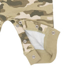 Close-up of a baby garment with a beige, green, and brown camouflage pattern, featuring metal snap closures and a white inner lining.