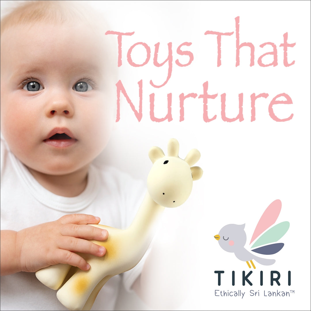A baby in a white shirt holds a cream-colored giraffe toy against a white background, with the text 'Toys That Nurture' and the TIKIRI brand logo visible.