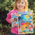 Child holding a colorful sketchbook and coloring book with nature-themed designs.
