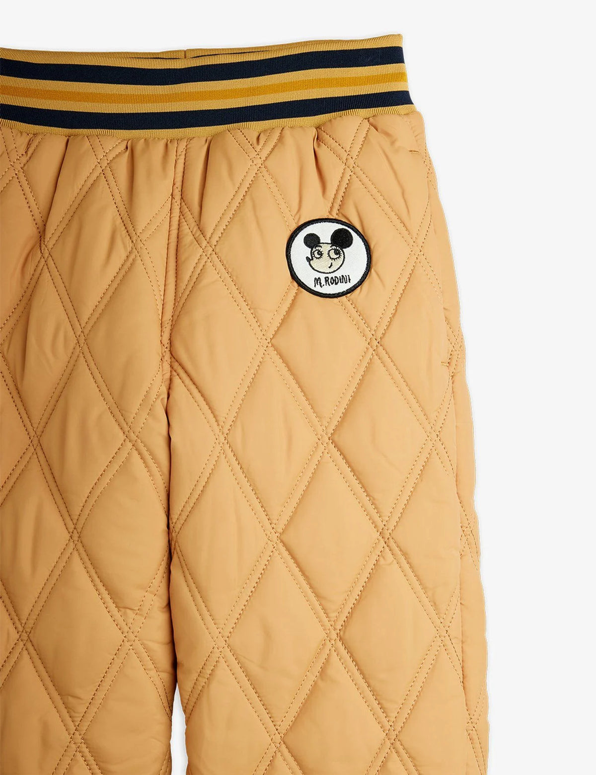 Quilted beige pants with a logo patch on a white background