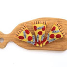 Wooden cutting board with felt pizza slices on a white background