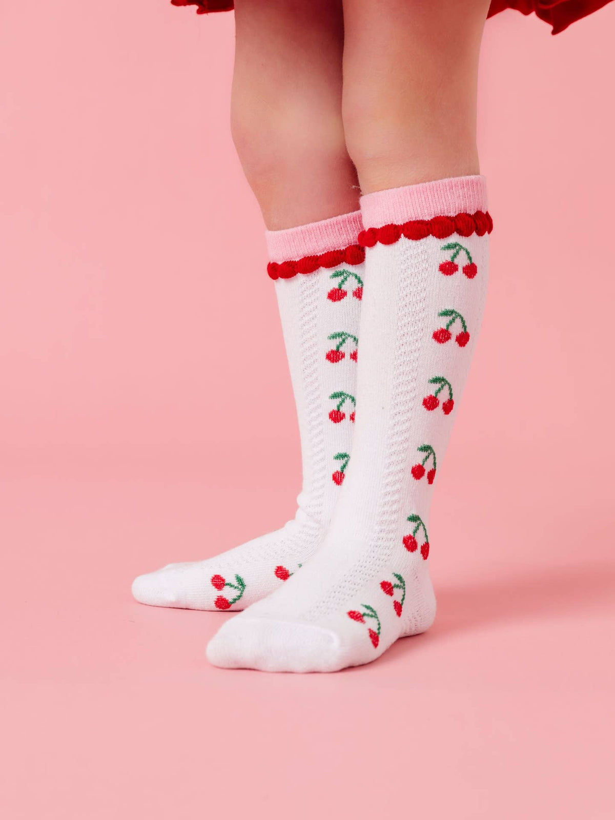 White socks with red cherry pattern on a pink background