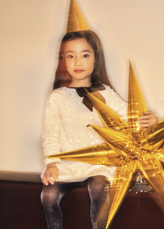 Young girl wearing a gold party hat with a large gold star decoration.