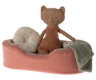 Knitted cat toy on a pink cushion with a blanket and polka dot pillow on a white background