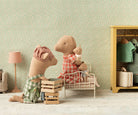 Two plush toys in a room with a floral wallpaper and a yellow cabinet.