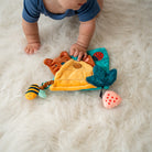 Baby playing with a colorful toy on a soft surface